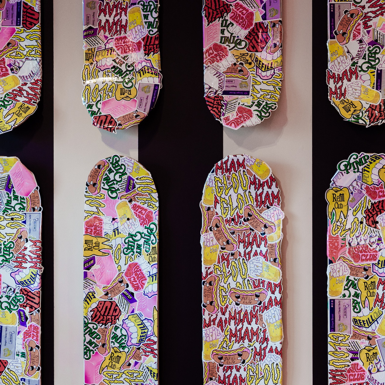 Colorful abstract vertical panels with floral and geometric patterns on black and white striped wall