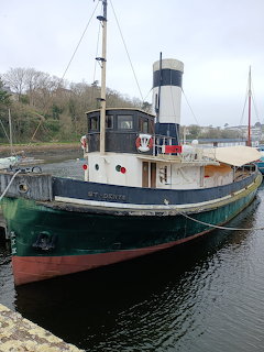 Historic steam tug boat moored at dock with smokestack and wheelhouse