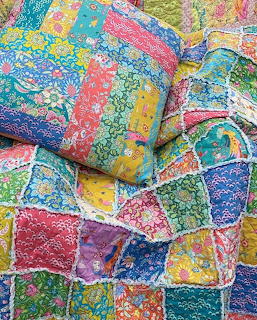 Colorful patchwork quilt with floral fabric squares in pink, blue, yellow, and green arranged in traditional pattern