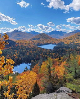 Autumn mountain landscape with colorful fall foliage, lakes, and distant peaks under a blue sky