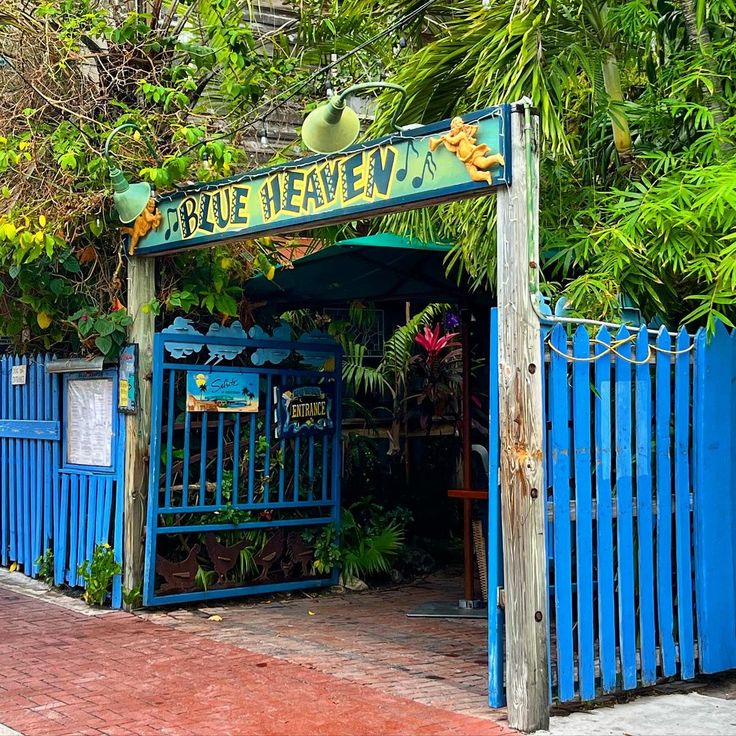 Blue Heaven sign above a blue gate framed by dense tropical greenery