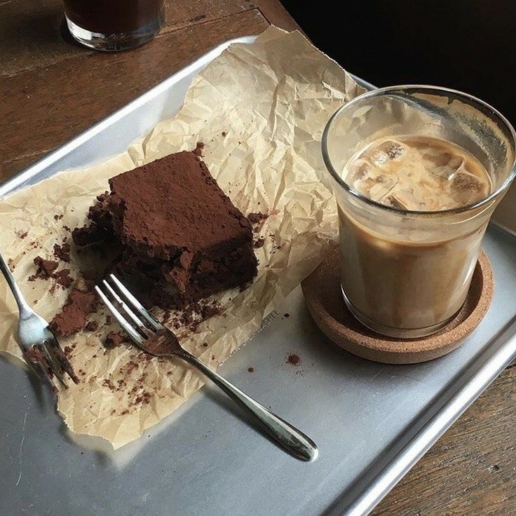 Chocolate brownie and iced coffee on a metal tray with a fork