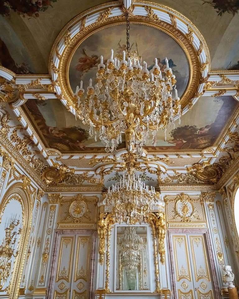 Opulent baroque palace room with large crystal chandelier and gold decorated ceiling