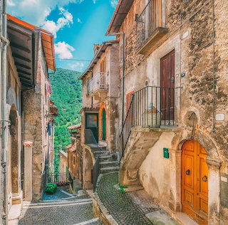 Narrow stone street with rustic buildings and stairs in an old Italian village