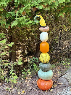 Tall stack of various sized pumpkins and gourds in autumn colors balanced vertically outdoors