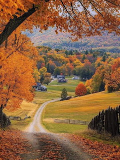 Dirt road through orange fall trees overlooking farm valley with colorful autumn hillsides
