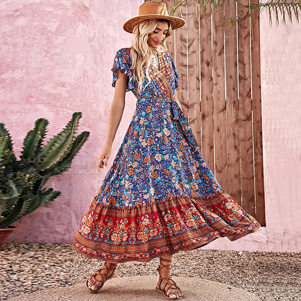 Woman in a long floral boho dress and straw hat by a pink wall, cactus, and wooden door