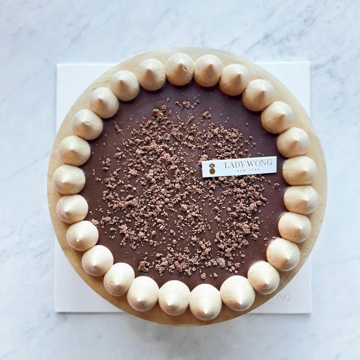 Top view of a round chocolate cake with meringue border and cocoa crumb topping