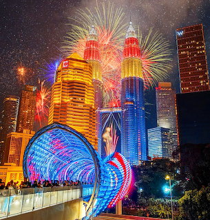Colorful fireworks exploding over illuminated Kuala Lumpur city skyline with Petronas Towers at night
