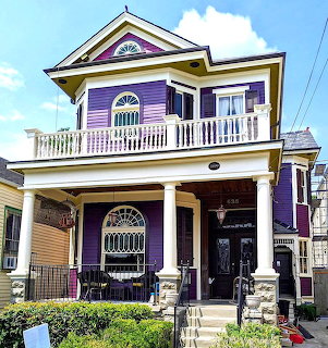 Purple Victorian house with white porch railings and ornate architectural details