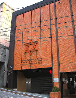 Orange brick synagogue building with large Star of David and Hebrew inscription on facade