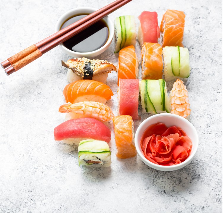 Assorted nigiri sushi platter with salmon, tuna, shrimp, soy sauce, chopsticks and pickled ginger on marble surface