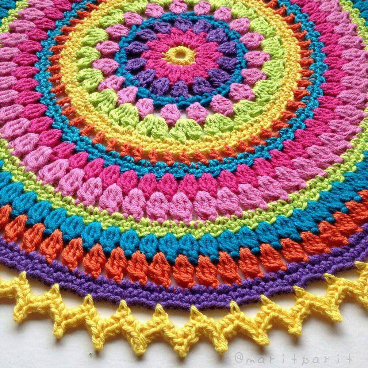 Rainbow colored crochet mandala with concentric circular patterns in pink, yellow, blue, orange and purple yarn