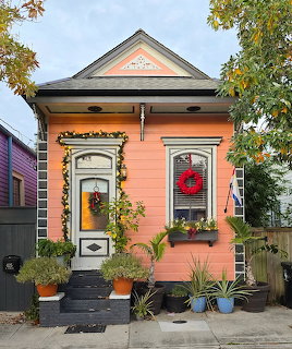 Peach cottage with Christmas decorations and wreaths, potted plants on front steps