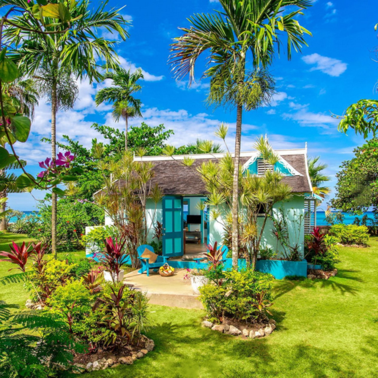 Turquoise cottage with palm trees and tropical garden in Jamaica