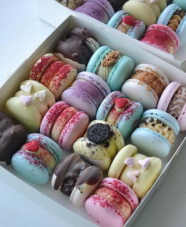 White box filled with colorful decorated macarons in pastel shades with various toppings