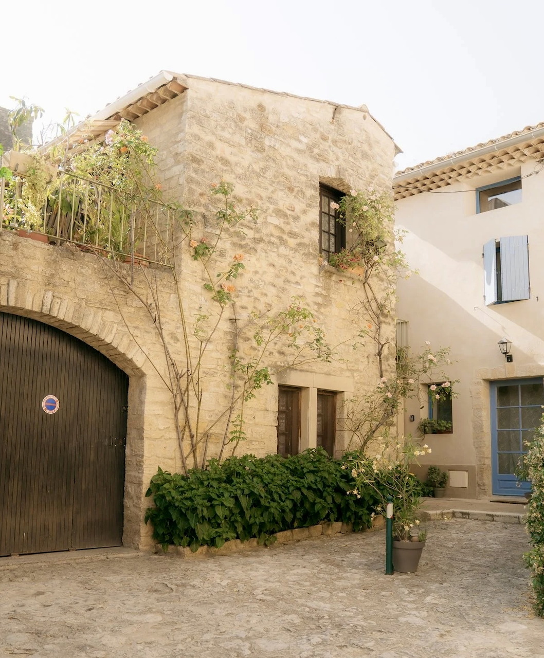 Rustic stone village house with shutters, courtyard, and climbing plants