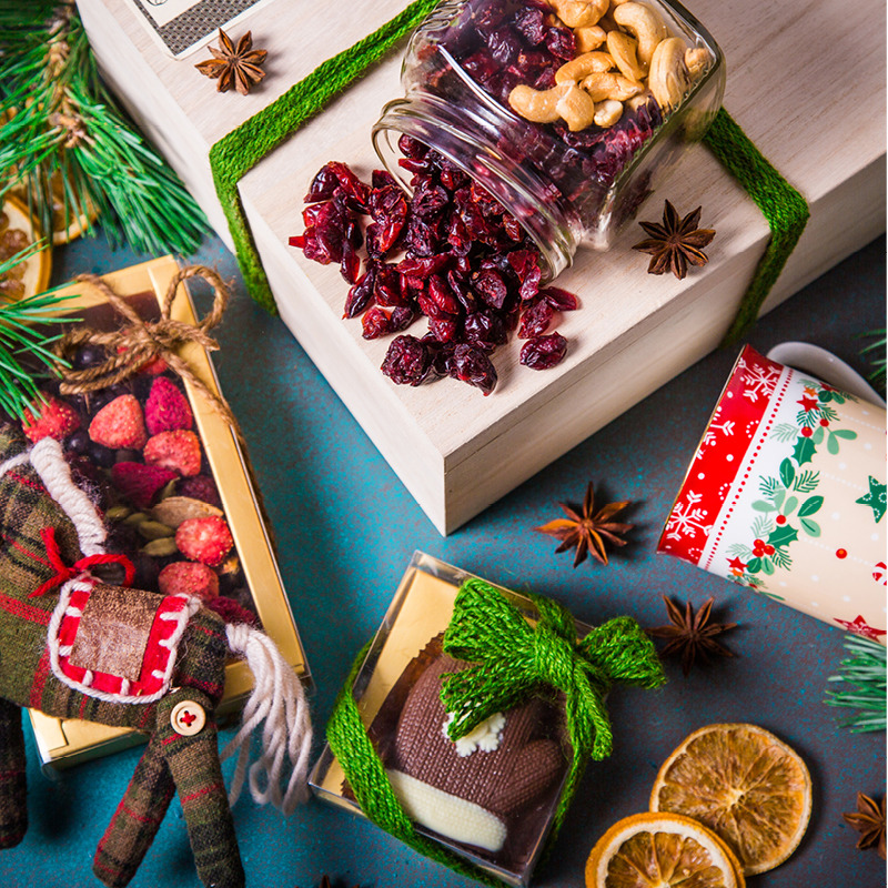 Christmas flatlay with gifts, cranberries, gingerbread cookie, pine branches, and dried orange slices