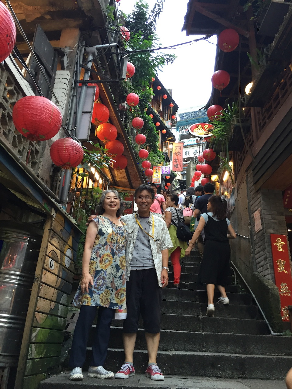 Two people standing on Jiufen's lantern-lined stone steps in Taiwan