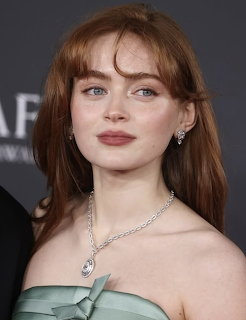 Portrait of Sadie Sink in a strapless green dress with necklace and earrings