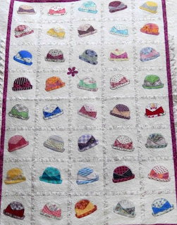Colorful patchwork quilt with embroidered hats in grid pattern on white background