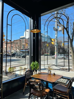 Cozy café interior with arched windows, wooden table, and street view on a sunny day