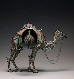 Bronze camel sculpture with open howdah and hanging bell, green patina accents and chains
