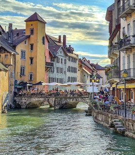 Old European town with canal, stone bridge, colorful buildings, and outdoor cafes