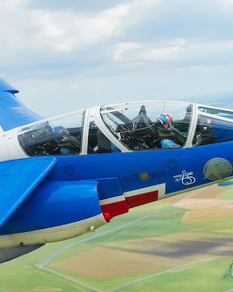 Close-up of a blue Patrouille de France Alpha Jet cockpit in flight over green fields
