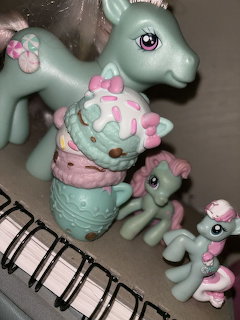 Mint green toy ponies with pink accents and a matching ice cream cone figurine on a notebook