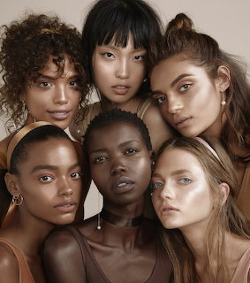 Close-up portrait of six women with diverse complexions and natural hairstyles grouped together