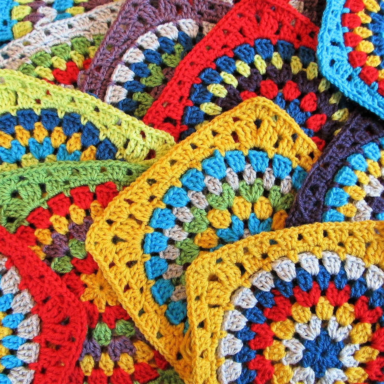Close-up of colorful crocheted granny squares in red, yellow, green, blue, and purple yarn