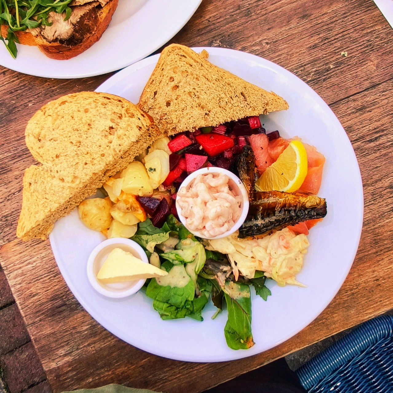 Overhead view of a breakfast plate with toast, eggs, grilled vegetables, greens, and dipping sauce