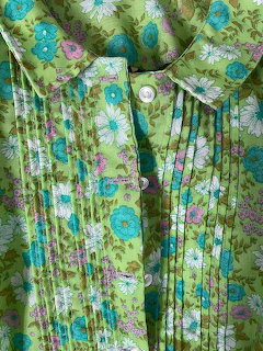 Close-up of a green floral blouse with Peter Pan collar, pintuck pleats, and white buttons