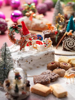Christmas cake and cookies on festive table with ornaments and miniature trees