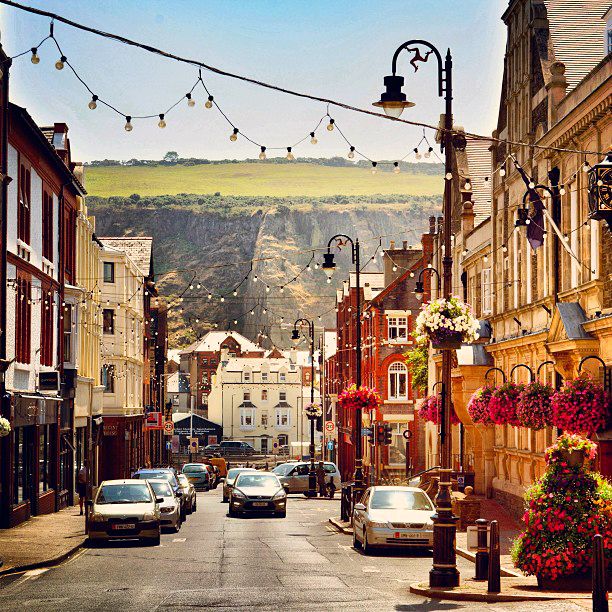 Street view of Douglas, Isle of Man with historic buildings, cars, and hills in background