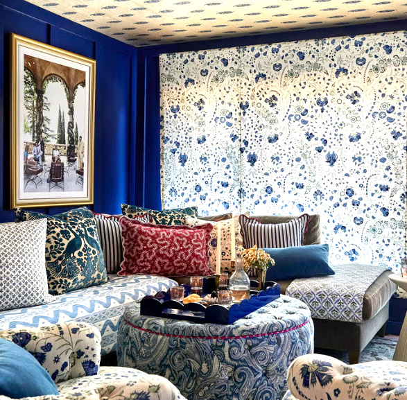 Blue sitting room with patterned wallpaper, framed art, and cushioned benches with many pillows