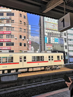 Japanese commuter train at station platform with city buildings in background
