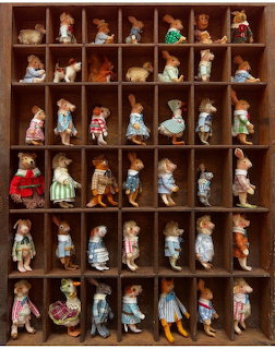 Collection of small vintage dolls displayed in wooden cubby shelf compartments