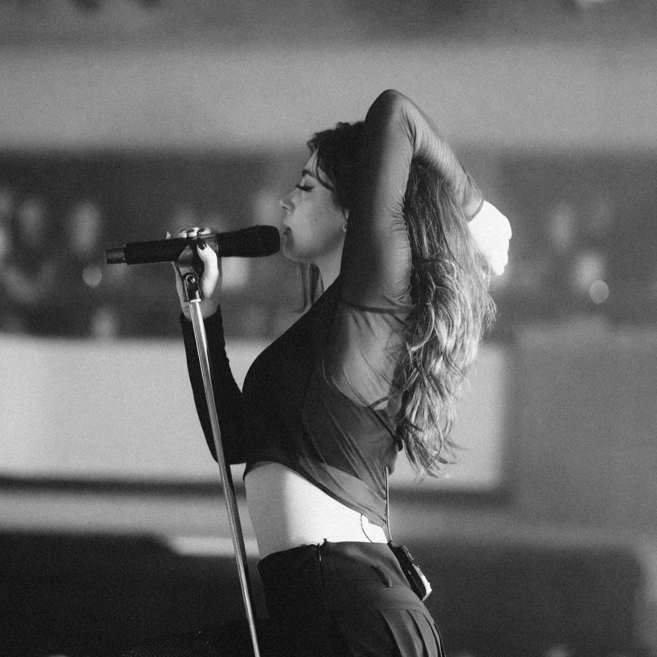 Black-and-white photo of singer Chrissy Costanza performing with a microphone on stage