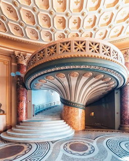 Spiral staircase with ornate ceiling and decorative floor patterns in an Art Nouveau building interior