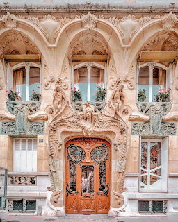 Ornate Art Nouveau building facade with sculptural details and carved wooden door in Paris