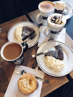 Overhead view of coffee cups, cheesecake slices, and a pastry on a wooden table