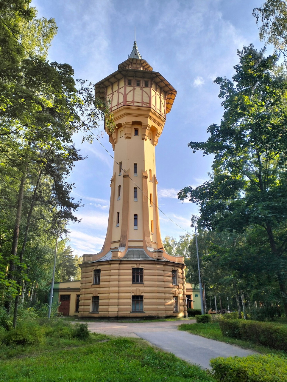 Historic water tower surrounded by trees and greenery under a blue sky