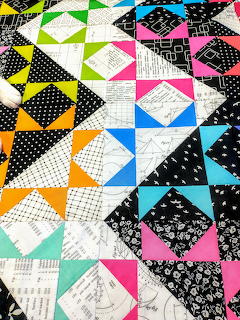 Colorful geometric quilt blocks with varied patterns and bright colors arranged in a patchwork design