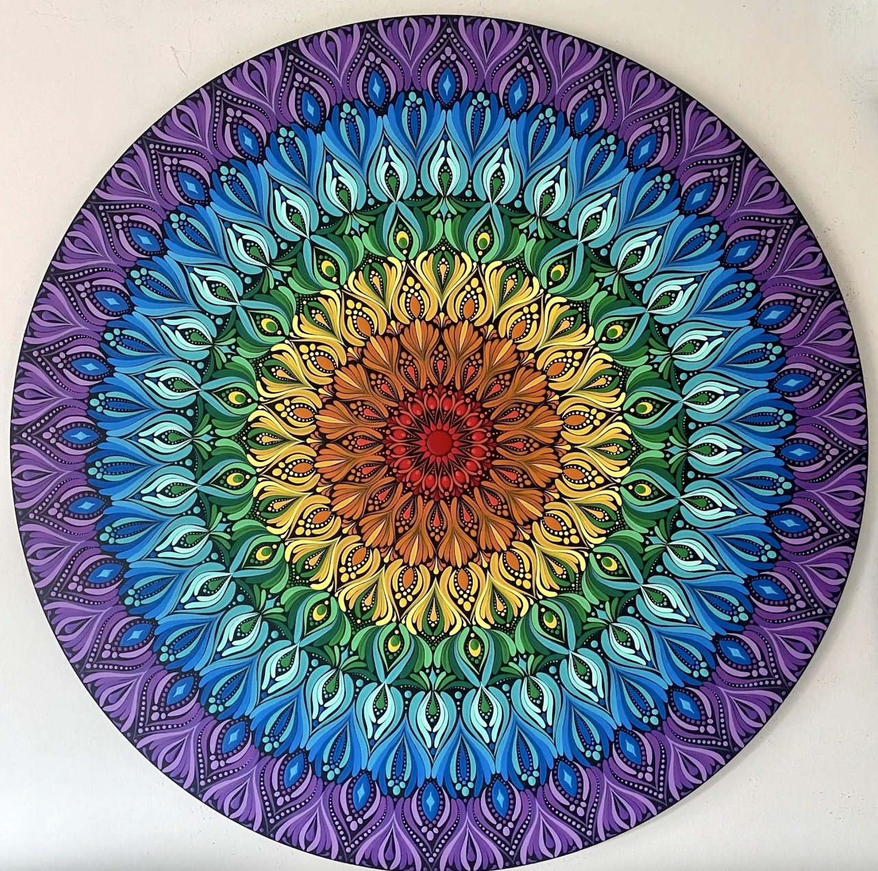 Colorful circular mandala with concentric rings of dot patterns radiating from orange center to purple edges