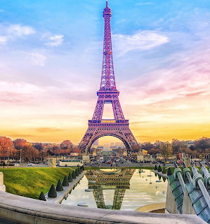 Eiffel Tower at sunset with pink and golden sky, gardens and fountains in foreground