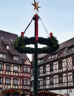 Tall maypole with star and wreaths in square with timber-framed houses