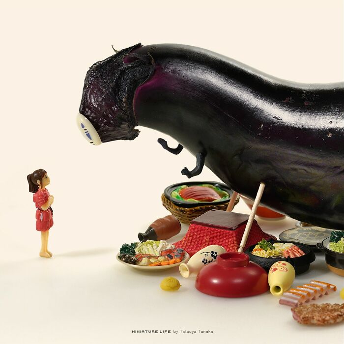 Miniature person standing before a giant eggplant towering over tiny food dishes on a light background