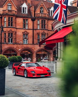 Red Ferrari F40 supercar parked outside a classic red-brick building with a British flag in London